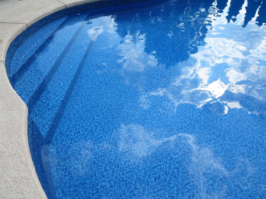 Blue Siesta pool liner with sunlight dancing over blue water and curved pool steps